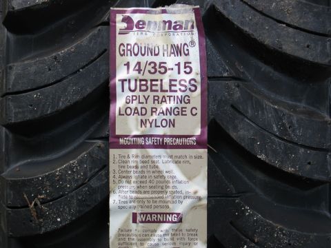 1995 Ford Bronco - Close-up of a Denman Ground Hawg tire, showing its tread pattern and a label with mounting safety precautions.