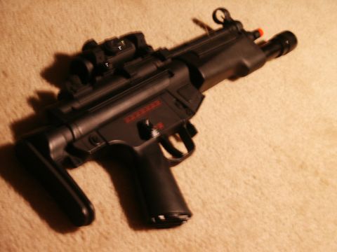 1991 Ford Bronco - A black submachine gun with red markings and an attached optic sight is shown from a side angle.