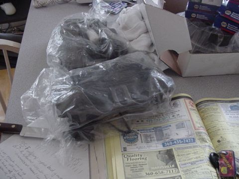 1987 Ford Bronco - Car parts wrapped in plastic on a table with a newspaper and handwritten notes visible.