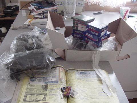 1987 Ford Bronco - Various car parts are laid out on a table, alongside an open phone book and a landline phone.