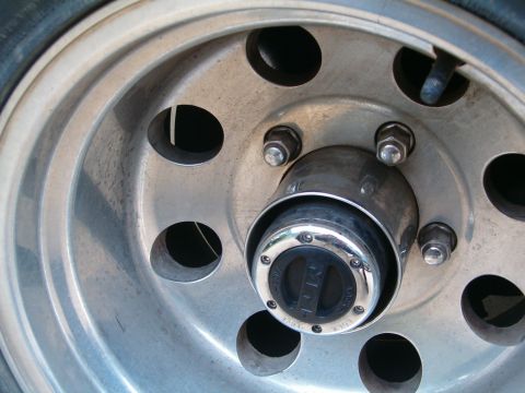 1996 Ford Bronco - Close-up of a vehicle's wheel hub, showing lug nuts and a locking mechanism.