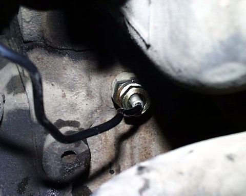 1988 Ford E250 - A close-up view of a sensor and wire connected to a vehicle's engine block.