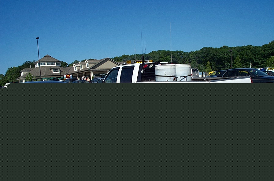 White truck with large white tanks in bed, parked in lot