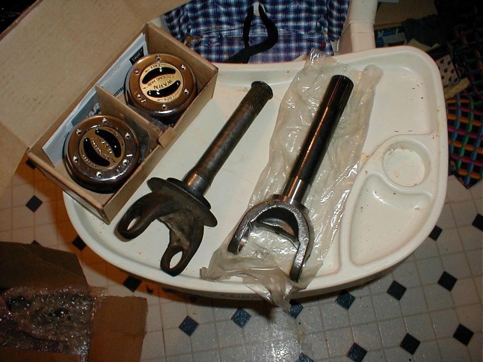 Warn locking hubs in box next to two splined front axle shafts with U-joint yokes
