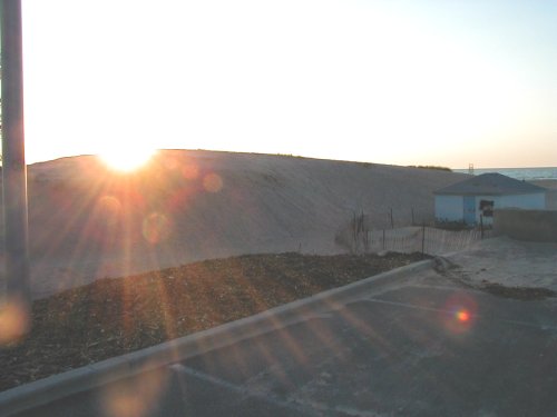 Dune and small building by the ocean at sunset