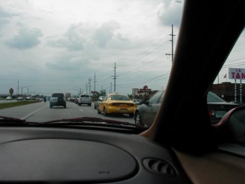 1997 Ford Taurus - Traffic moves slowly on a highway under a cloudy sky. A yellow taxi is visible ahead.