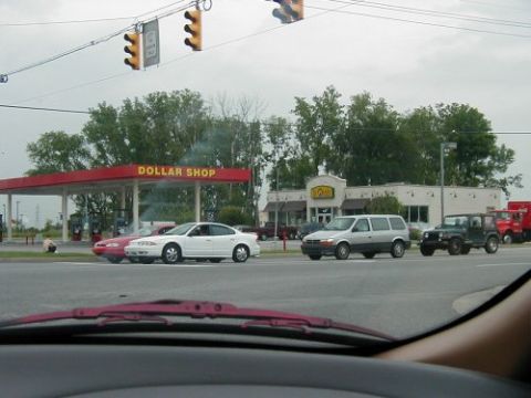 1997 Ford Taurus - Multiple vehicles are seen at an intersection in front of a Dollar Shop and a restaurant.