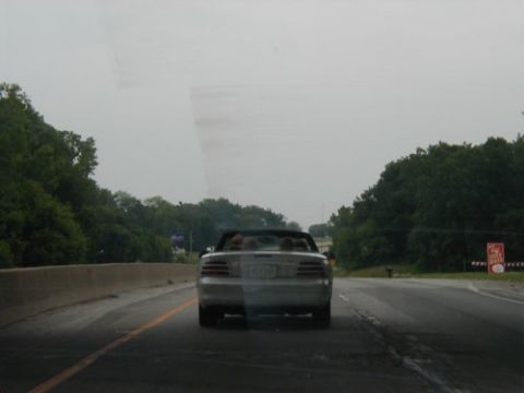 1997 Ford Taurus - Silver convertible seen from behind on a highway under an overcast sky.