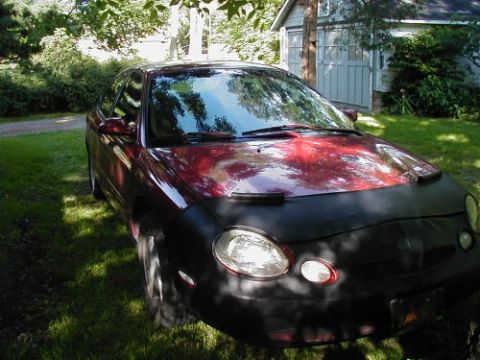 1997 Ford Taurus - A red 1997 Ford Taurus is parked on a grassy lawn in front of a shed.