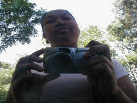 1997 Ford Taurus - A person takes a selfie in a car's side mirror while holding a digital camera, with trees reflected in the mirror.