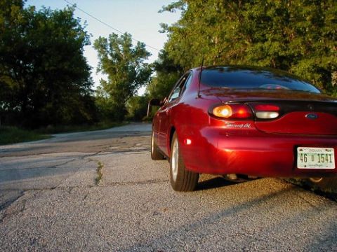 1997 Ford Taurus - Rear view of a red 1997 Ford Taurus parked on a rural road.