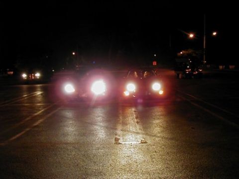 1997 Ford Taurus - Several vehicles are visible on a dark, wet road at night, with headlights on.