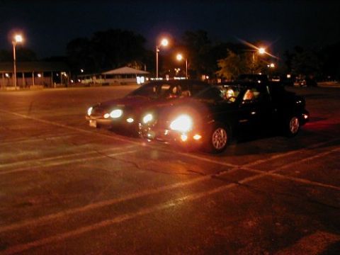 1997 Ford Taurus - Two cars are parked in a lot at night, illuminated by streetlights and their own headlights.