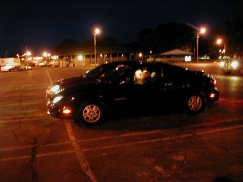 1997 Ford Taurus - Two vehicles are parked in a lot at night, with streetlights illuminating the scene.