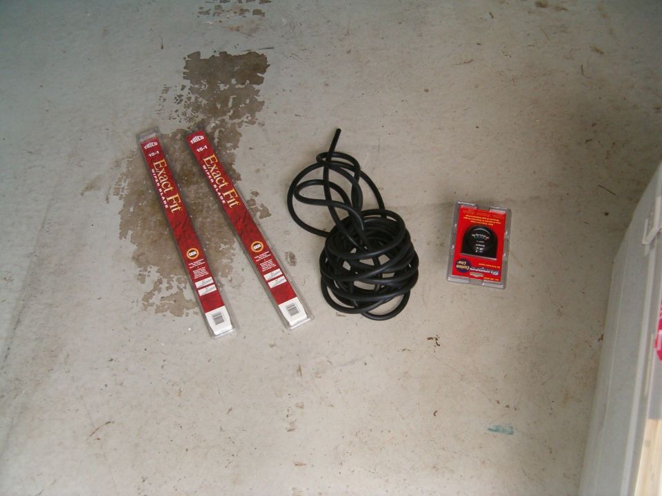 Two ExactFit packages, a coil of black tubing and a small boxed part laid out on a stained concrete floor