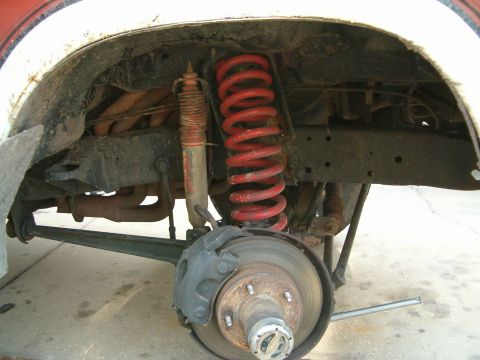 1979 Ford Bronco - Close-up view of the rear suspension and brake assembly on a 1979 Ford Bronco, highlighting the red coil spring and shock absorber.