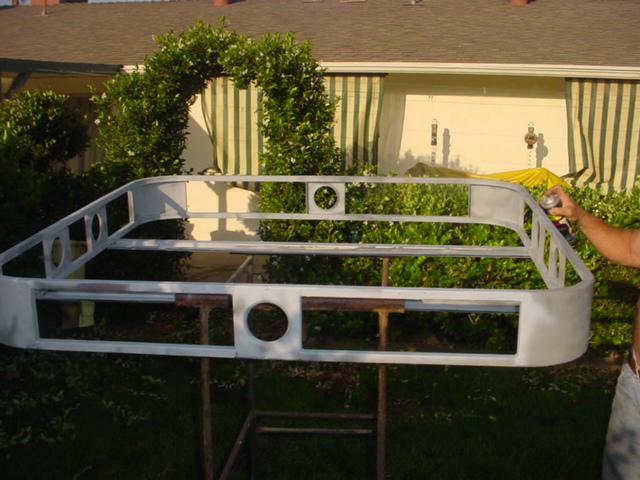 Primer-grey fabricated light bar with light cutouts on stands in a front yard
