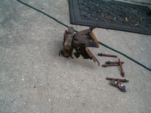 1979 Ford Bronco - Several heavily rusted vehicle components and fasteners are laid out on a concrete surface.