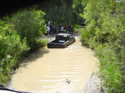 1993 Ford Bronco - Pickup truck navigates a water obstacle with onlookers present.