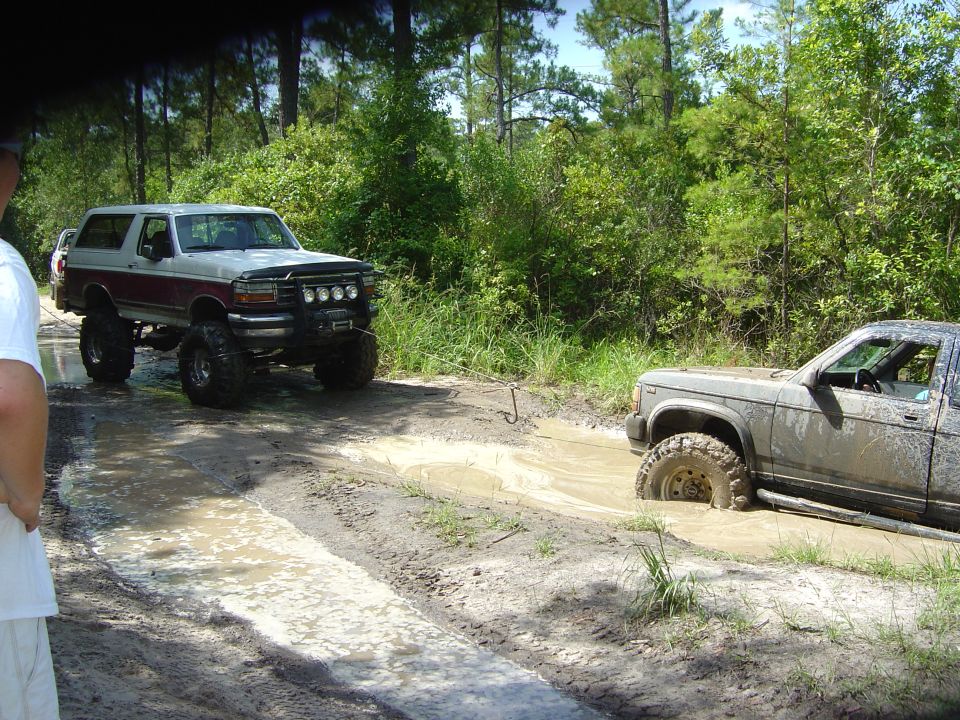 Lifted Bronco and a stuck truck in a muddy trail