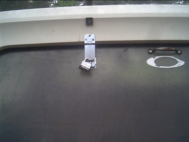 Close-up of a chrome latch and a handle hardware mounted on a flat fiberglass or plastic panel