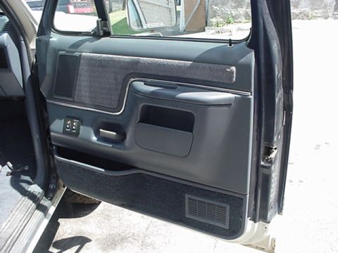 1989 Ford Bronco - Interior view of a vehicle's gray door panel, showing the armrest and storage compartment.
