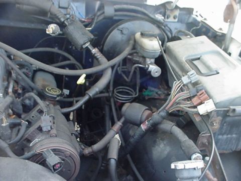 1989 Ford Bronco - A close-up view of a vehicle's engine bay, showing various hoses, wires, and mechanical components.