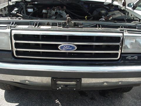 1989 Ford Bronco - Close-up of a Ford truck's front grille and engine bay, a 4x4 badge.