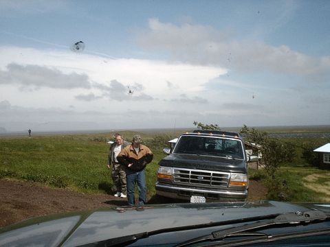 1996 Ford Bronco - A black Ford F-Series truck is parked on a dirt road with two men standing next to it under a cloudy sky.