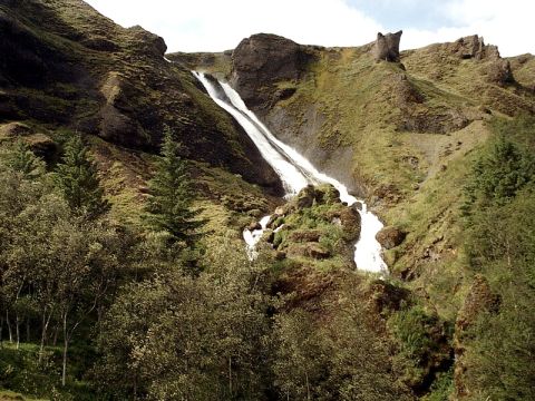 1996 Ford Bronco - A waterfall flows down a verdant, mountain slope under a cloudy sky.