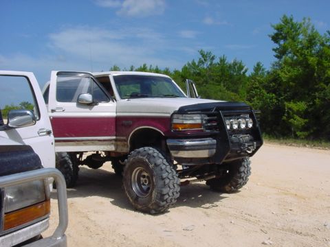 1986 Ford Bronco - Modified 1992 Ford Bronco with large tires and a custom front bumper sits off-road.