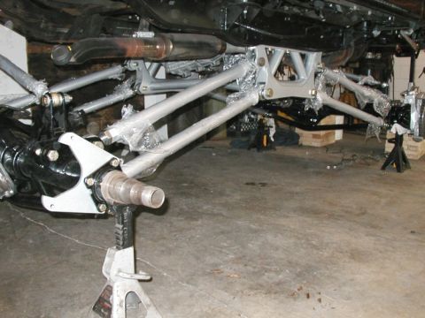 1994 Ford Bronco - Custom suspension components and rear axle assembly are shown supported by jack stands in a garage.