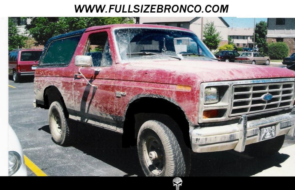 Faded red two-door Ford Bronco with peeling paint parked in a lot