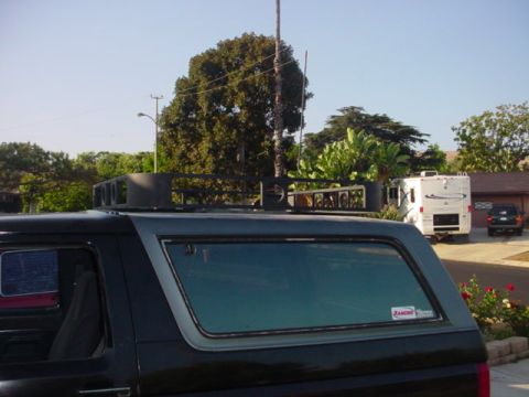 1988 Ford Bronco - A black Ford Bronco with a roof rack is parked in a driveway next to an RV and another vehicle.