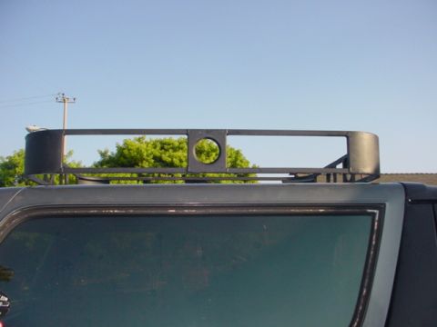 1988 Ford Bronco - Aftermarket roof rack with a distinctive circular cutout is mounted on the top of a dark-colored SUV.
