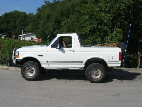1992 Ford Bronco - Side view of a white 1992 Ford Bronco, showing its lifted suspension and off-road tires.