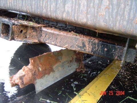 1986 Ford Bronco - Close-up of a heavily damaged trailer hitch receiver, covered in mud and rust.