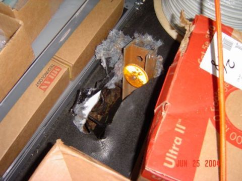 1986 Ford Bronco - A close-up view of a damaged metal component, possibly from a vehicle, amidst debris and packaging materials.