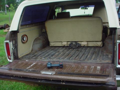 1979 Ford Bronco - The cargo area of a 1979 Ford Bronco shows a folded rear seat and a dumbbell on the floor.
