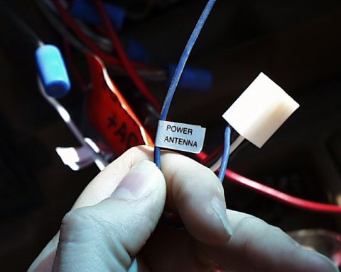 1988 Ford E250 - A hand holds a wire labeled 'POWER ANTENNA' amidst a tangle of other wires.