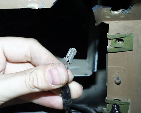 1988 Ford E250 - Close-up of a hand holding a wire connector, with a metal bracket visible in the background.