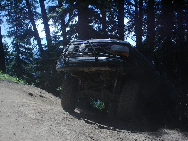 SUV with a brush guard and off-road tires on a dirt path in the woods