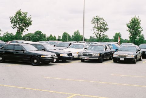 1998 Ford Crown Victoria - Several Ford Crown Victorias are parked in an outdoor lot under a cloudy sky.
