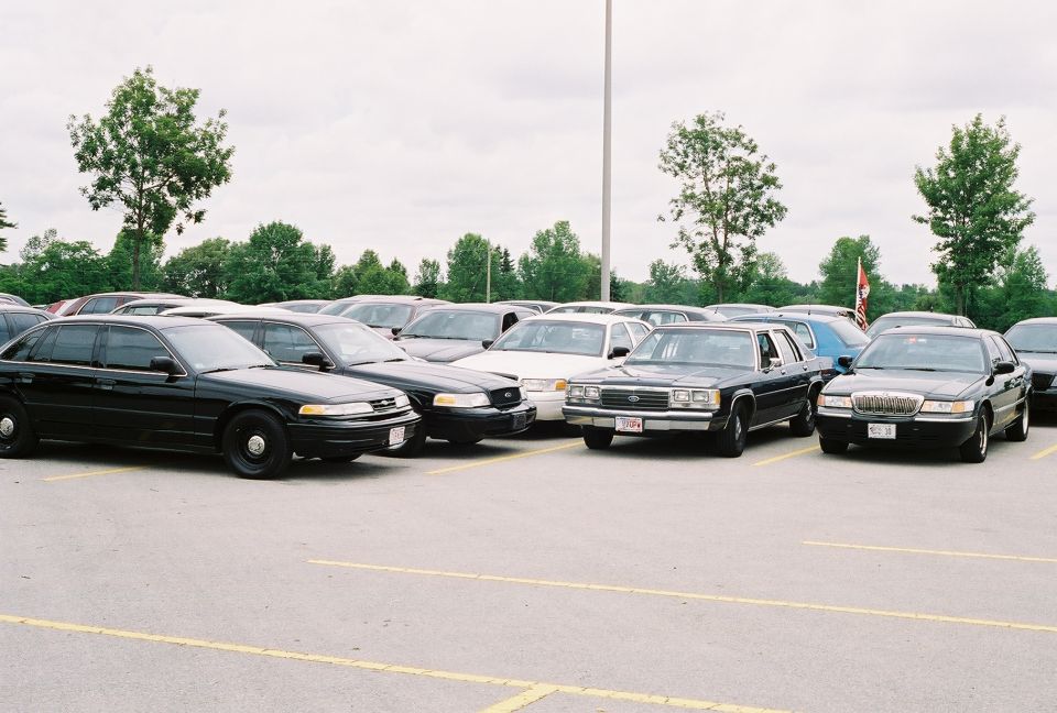 Black 1998 Ford Crown Victoria parked in a lot, front 3/4 view, showing police-style wheels and clear headlights