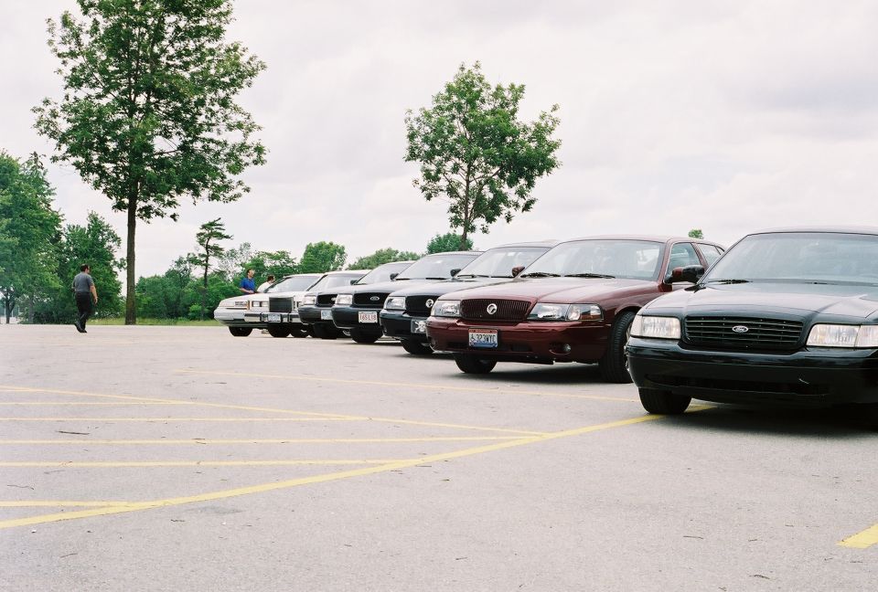 Several Ford Crown Victoria Police Interceptors parked in a lot. The front car is black
