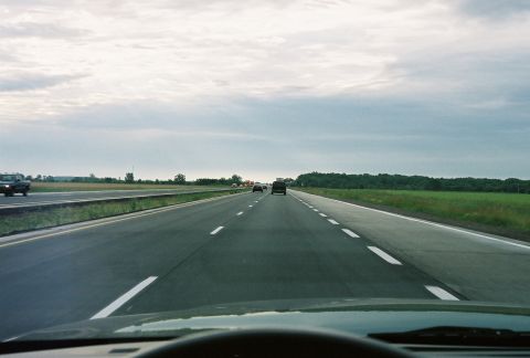 1998 Ford Crown Victoria - Driving on a multi-lane highway under a cloudy sky with other cars on the road.