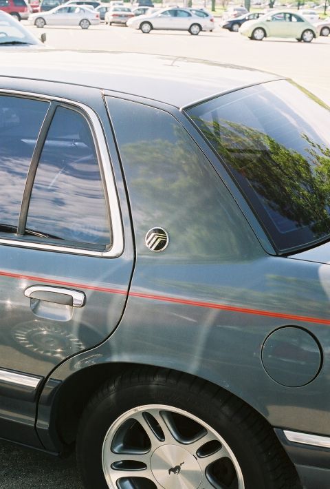 1998 Ford Crown Victoria - A Mercury Grand Marquis is parked in a lot with other vehicles visible in the background.