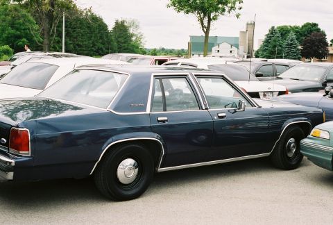 1998 Ford Crown Victoria - This sedan is parked in a lot with several other vehicles surrounding it.