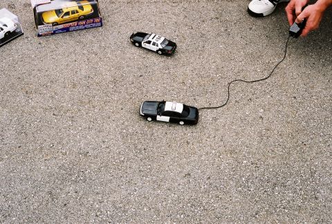 1998 Ford Crown Victoria - A toy police car is shown on a textured surface, with a remote control nearby.