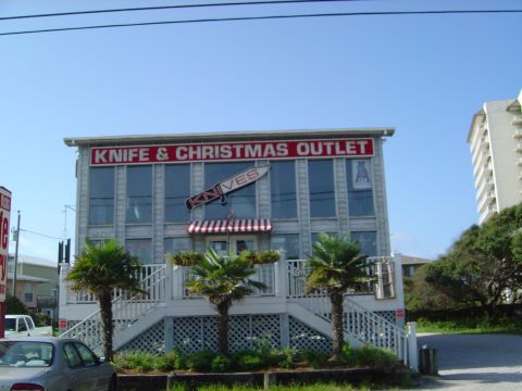 1986 Ford Bronco - A store with a sign reading 'Knife & Christmas Outlet' is shown with a large knife graphic above the entrance.